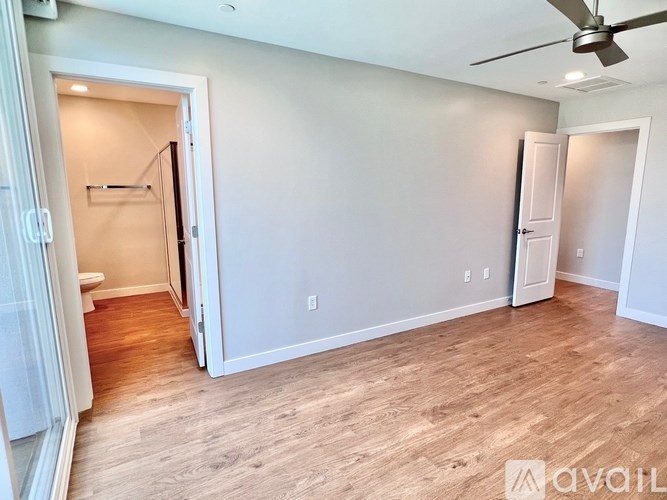 A room with a ceiling fan and light, a door, and a wall with a light switch.