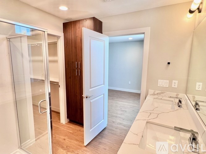 A bathroom with a walk-in shower, a sink, and a wooden door.