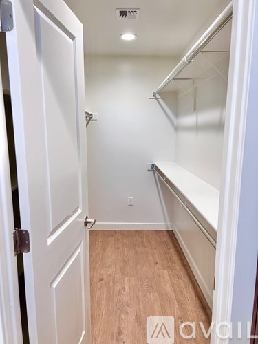 A white door is open to a small room with a shelf and a light on the ceiling.