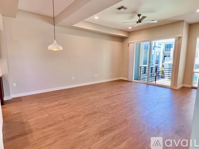 A spacious room with wooden flooring and a ceiling fan.