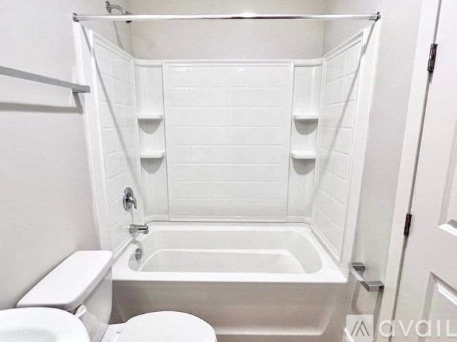 A white bathroom with a toilet, tub, and shelves.