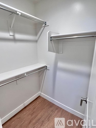 A white closet with two shelves and a wooden floor.