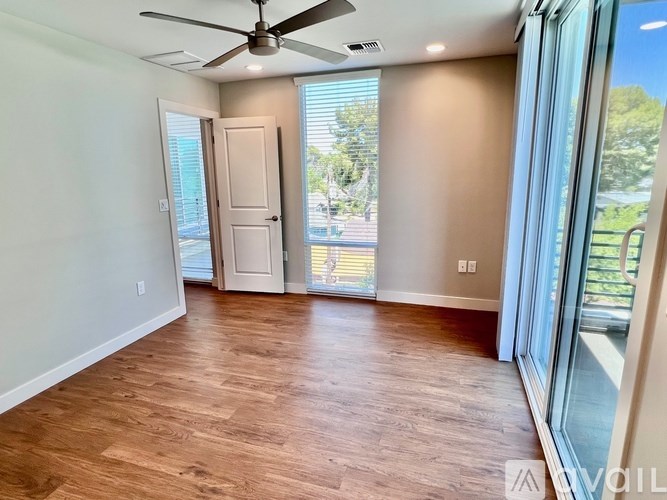 A room with a ceiling fan and sliding glass doors.