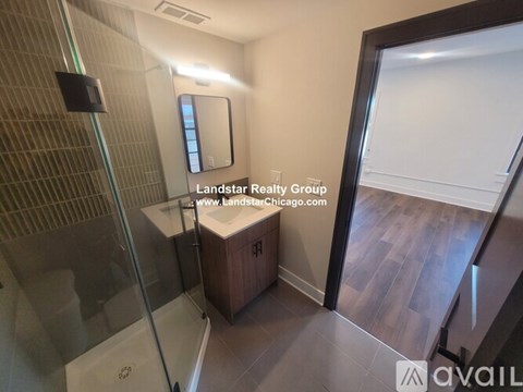 A bathroom with a glass shower stall and a wooden cabinet.