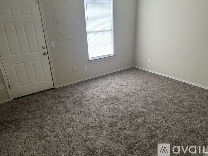A room with a carpeted floor, a door, and a window with blinds.