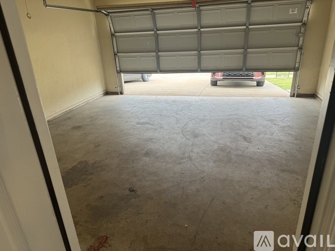 A car is parked in a garage with a closed grey door.
