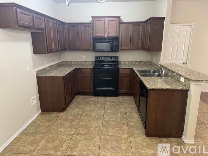 A kitchen with brown cabinets and a black stove top oven.