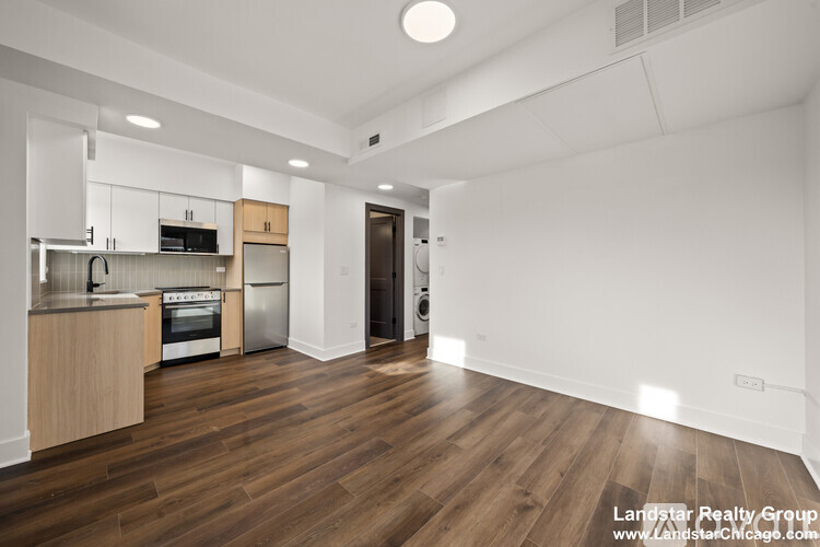 A room with wooden flooring and a staircase leading to another room.