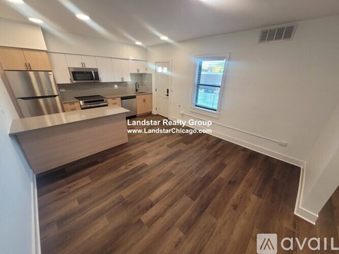 A kitchen with wooden floors and a window with blinds.