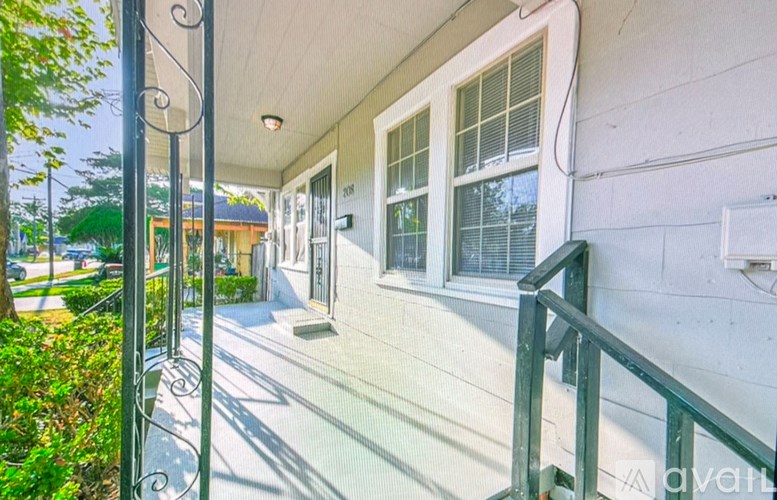 A white house with a green railing and a glass door.