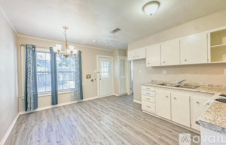 A kitchen with white cabinets and a wooden floor.