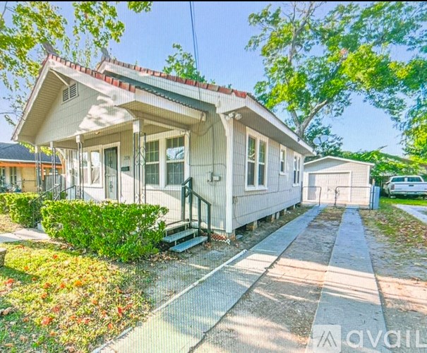 A white house with a red roof and a small garden in front.