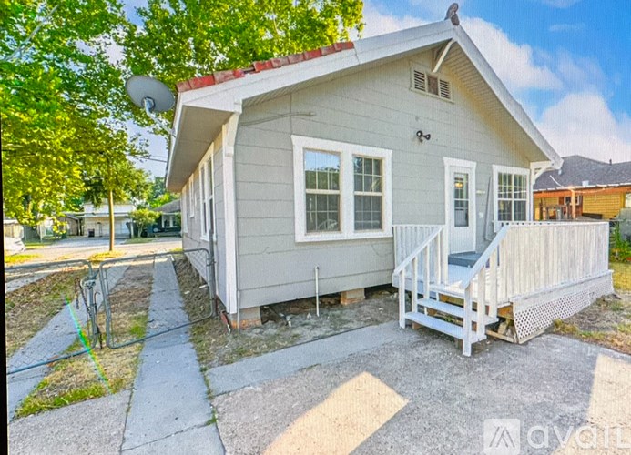 A small house with a porch and a satellite dish on the roof.