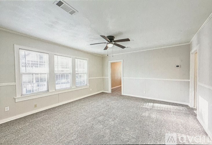 Empty room with a ceiling fan and a door.