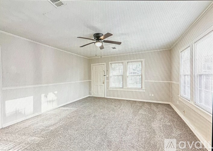 A room with a ceiling fan and carpeted floor.