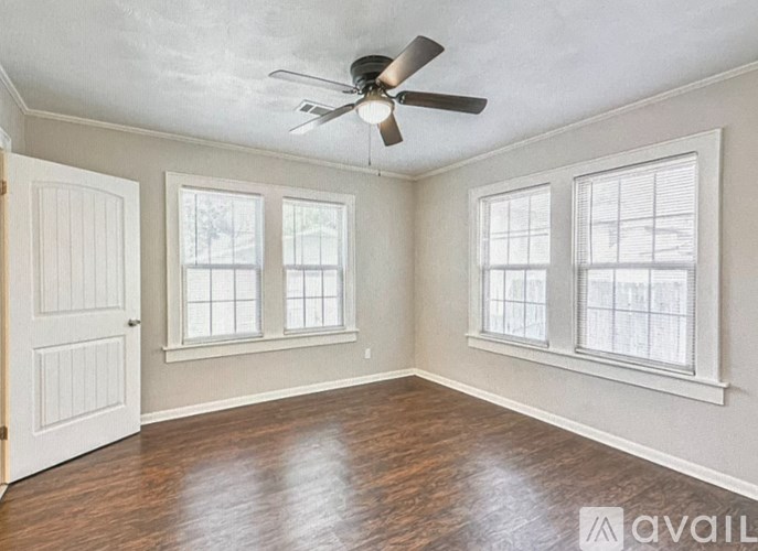 A room with a ceiling fan and three windows.
