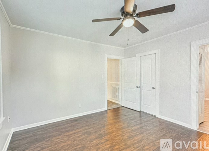 A room with a ceiling fan and wooden floors.