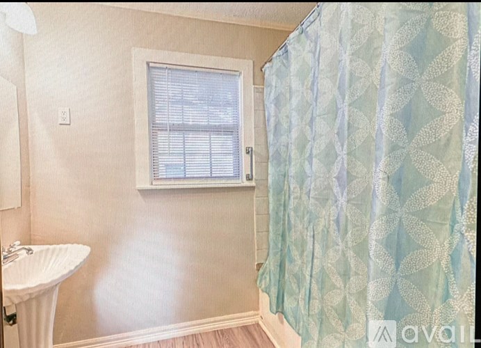 A bathroom with a white sink and a window with blinds.