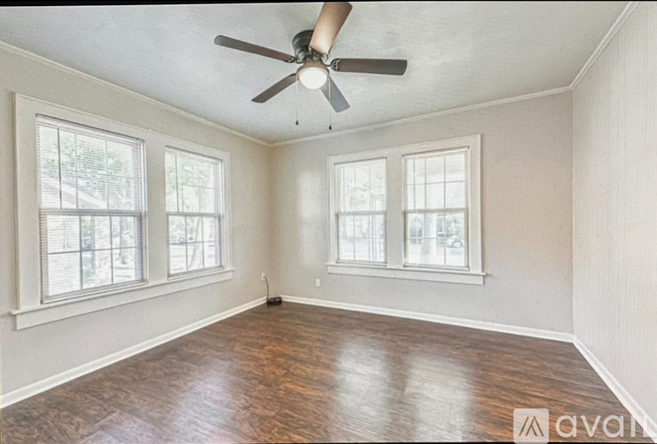 A room with a ceiling fan and three windows.