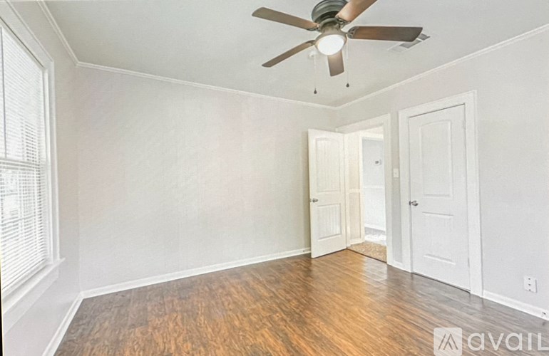 A room with a ceiling fan and wooden flooring.