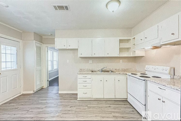 A kitchen with white cabinets and a white stove top oven.