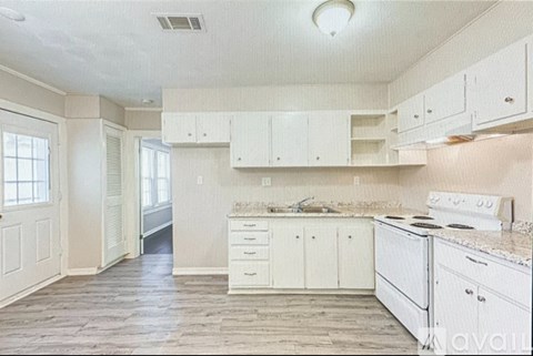 A kitchen with white cabinets and a white stove top oven.