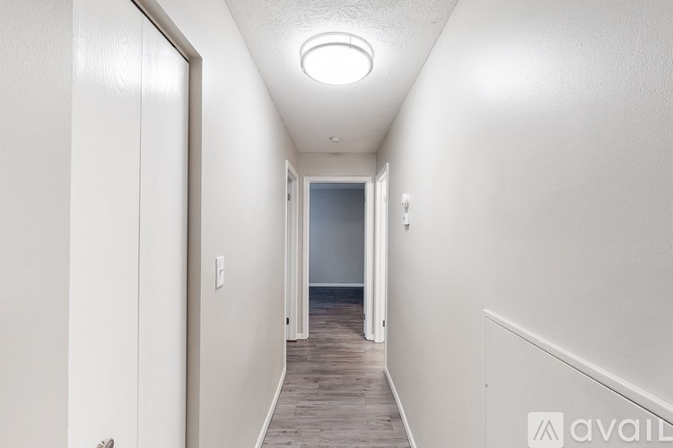 A long hallway with a door on the left and a light on the ceiling.