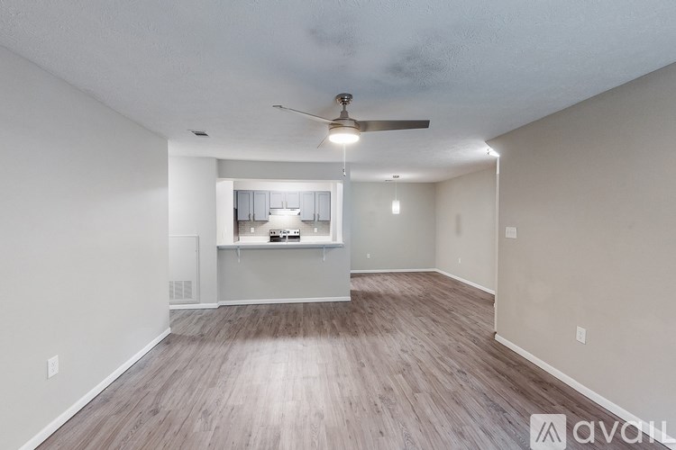 A spacious room with a ceiling fan and a kitchenette in the background.
