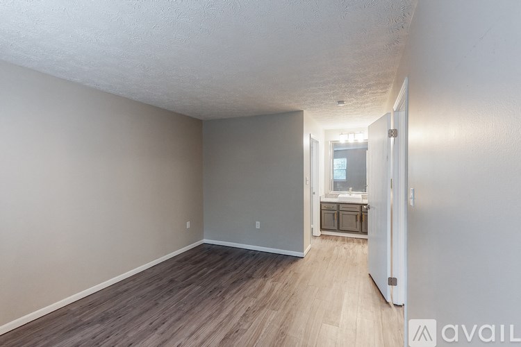 A room with a wooden floor and a white door leading to another room.