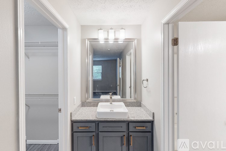 A bathroom with a sink, mirror, and cabinets.