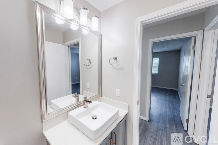 A bathroom with a white sink and a large mirror.