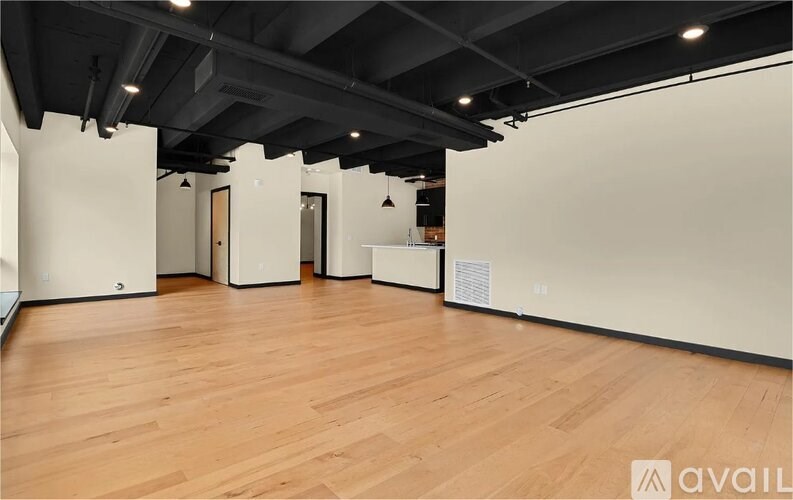A spacious room with wooden floors and white walls.