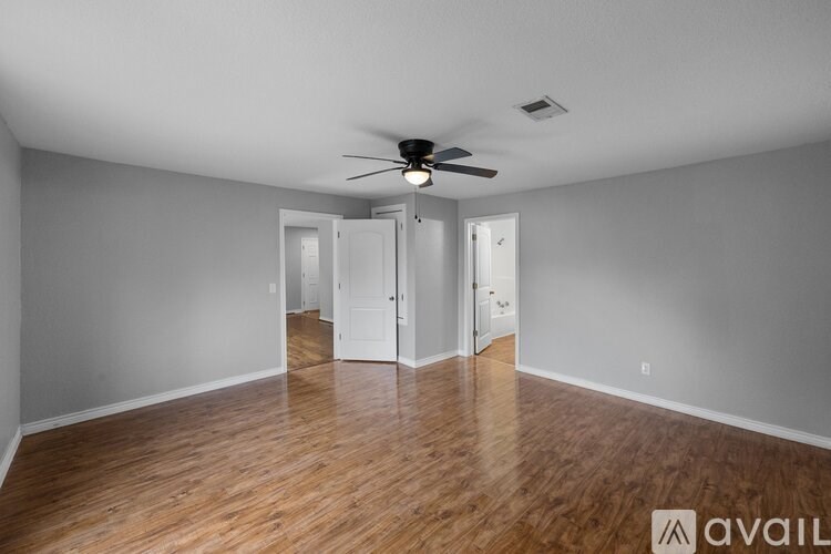 A room with a ceiling fan and wooden floors.