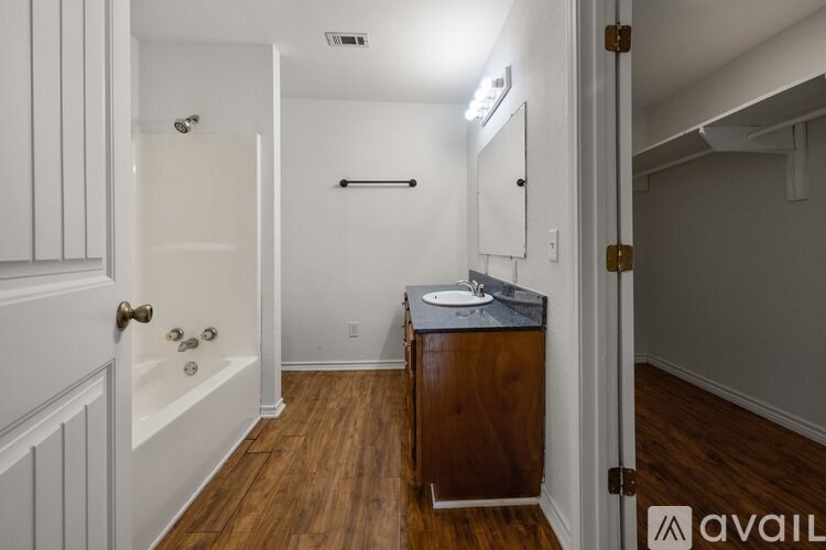 A bathroom with a sink, mirror, and bathtub.