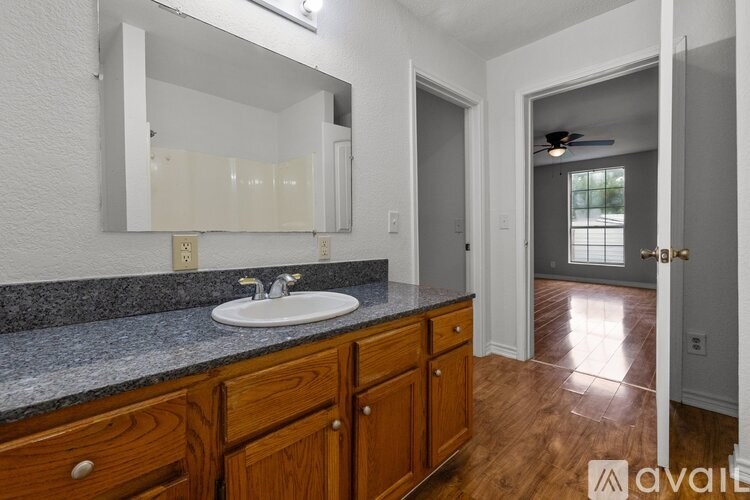 A bathroom with a sink, mirror, and wooden cabinets.