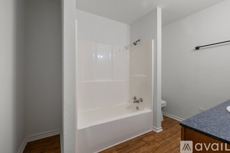A bathroom with a white tub and a wooden floor.