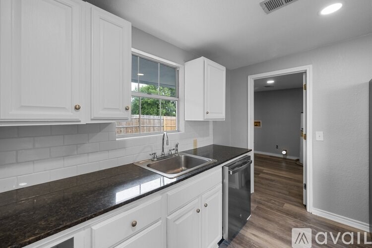 A kitchen with white cabinets and a black countertop.