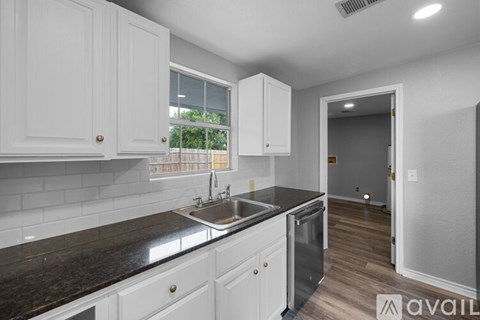 A kitchen with white cabinets and a black countertop.