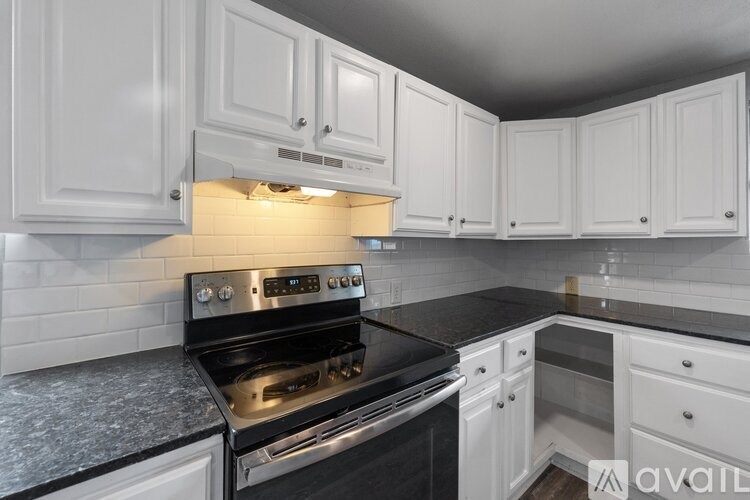 A kitchen with white cabinets and a black countertop.