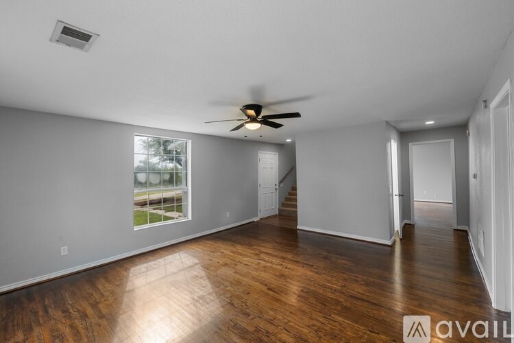 A spacious room with wooden floors and a ceiling fan.