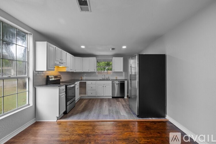A kitchen with white appliances and wooden floors.