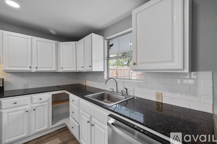 A kitchen with white cabinets and a black countertop.