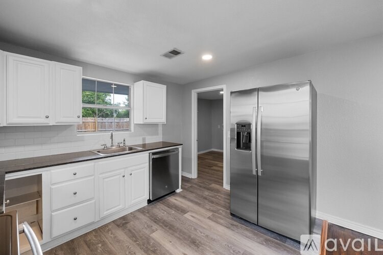 A kitchen with white cabinets and a wooden floor.