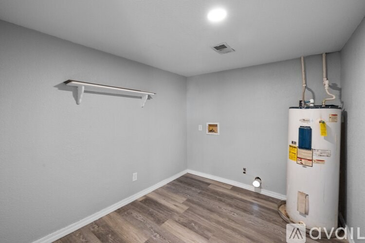 A room with a white wall and a wooden floor with a white shelf on the wall.