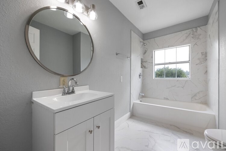 A bathroom with a white sink and a round mirror.