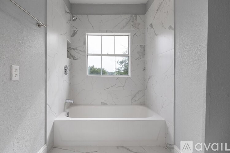 A white bathroom with a marble wall and a window.