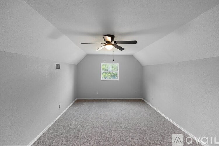 A room with a ceiling fan and a window.