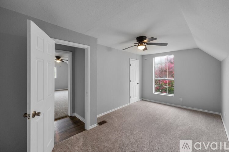 A room with a ceiling fan and carpeted floor.