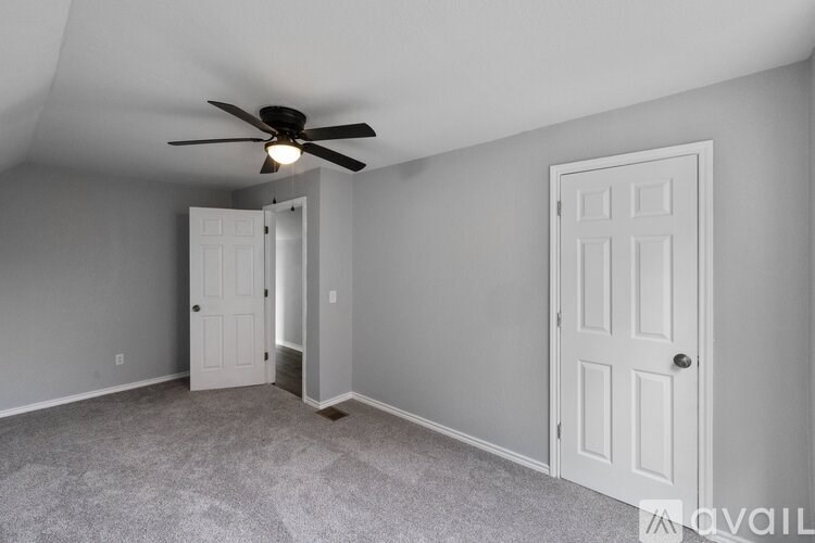A room with a ceiling fan and two doors.
