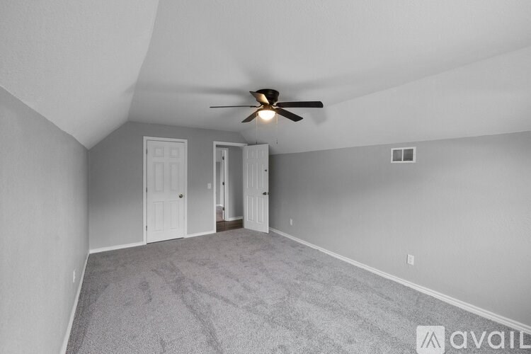 A room with a ceiling fan and carpeted floor.